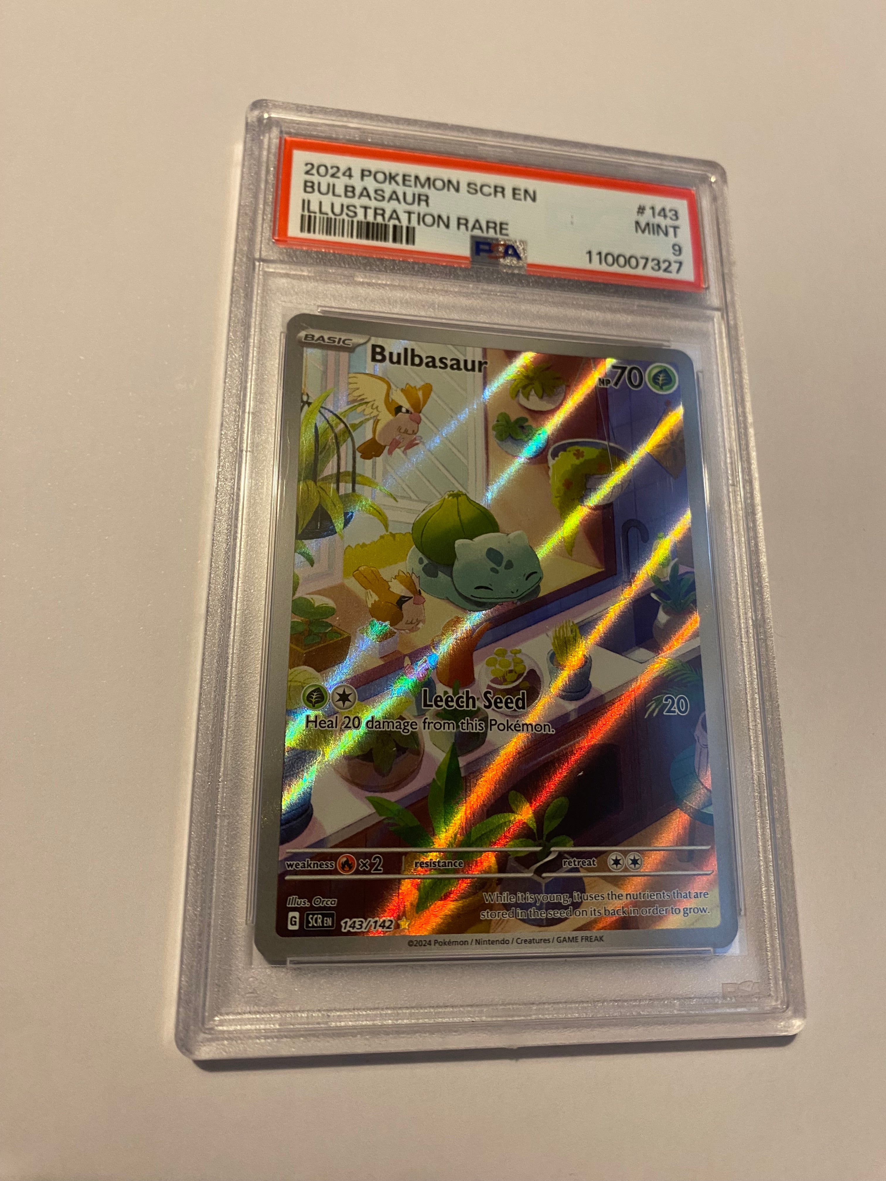 Holographic trading card in protective case on a plain background
