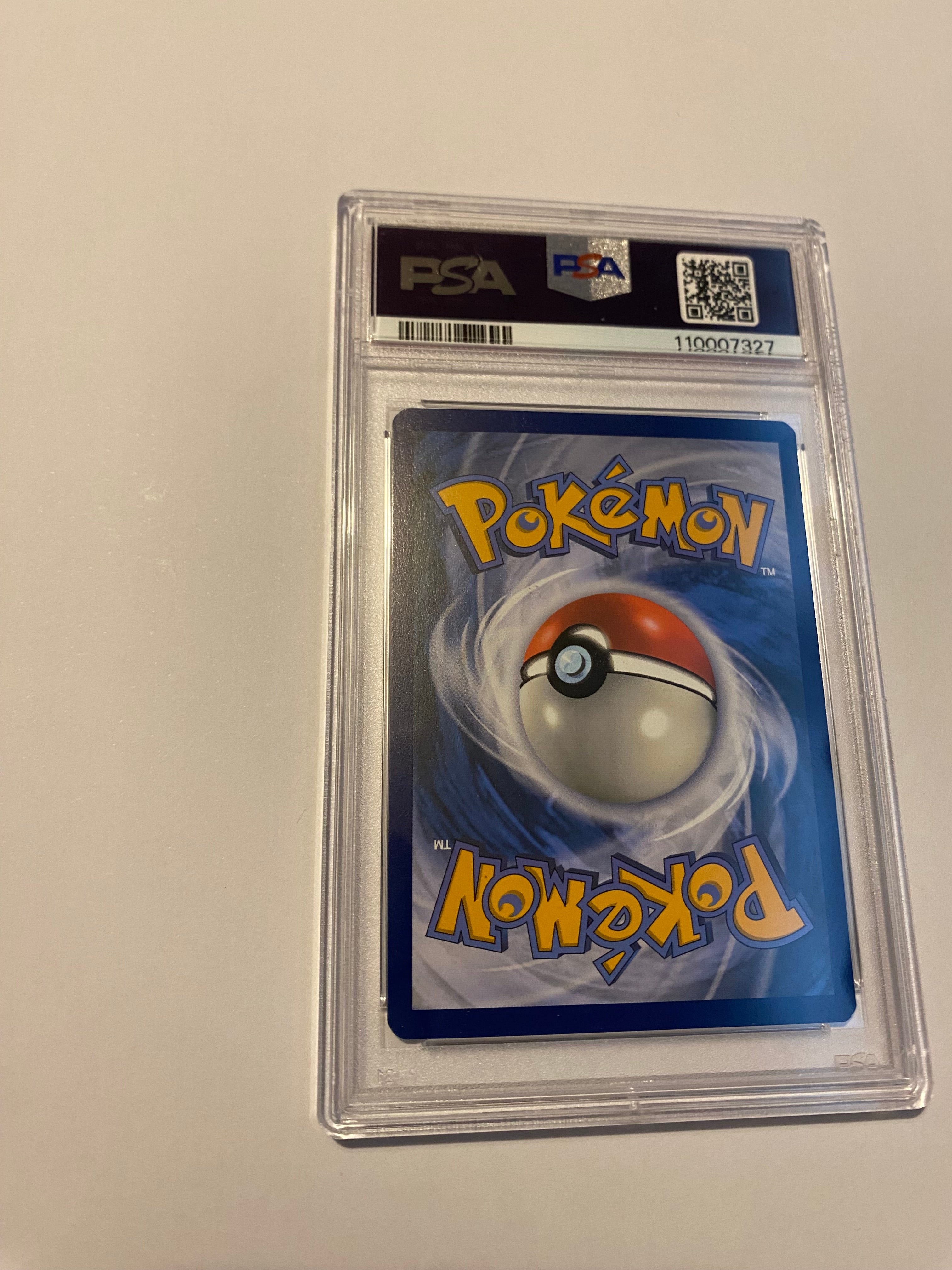 Pokémon trading card in a protective case with PSA grading on a light gray background